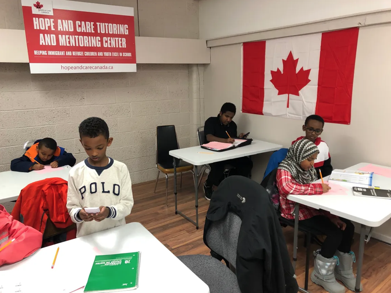 Students working independently at tables beneath a Canadian flag